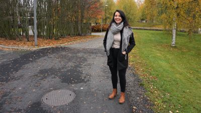 Kvinna i svart jacka står vid kanten av en cykelväg.