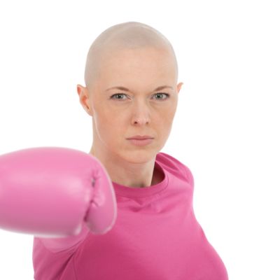 en kvinna med bröstcancer som har rosa kläder och rosa boxningshandskar på sig