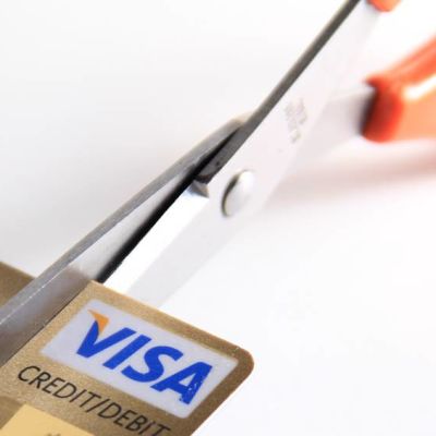Kuvassa sakset leikkaavat luottokortin kulmaa. 