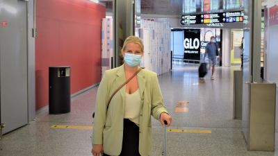 Sofia har just anlänt från Danmark och poserar med sin reseväska i korridoren på flygplatsen.