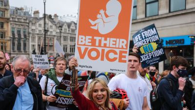 Människor protesterar mot abort. En kvinna håller upp en skylt med en bild på en baby där det står "Var deras röst".