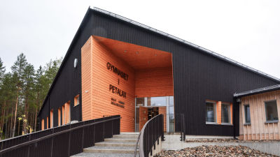 Trappa som leder upp till svart skolbyggnad i trä.