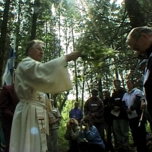 Katolinen isä pirskottaa vettä pyhiinvaeltajan päälle vaelluksen neljäntenä päivänä.