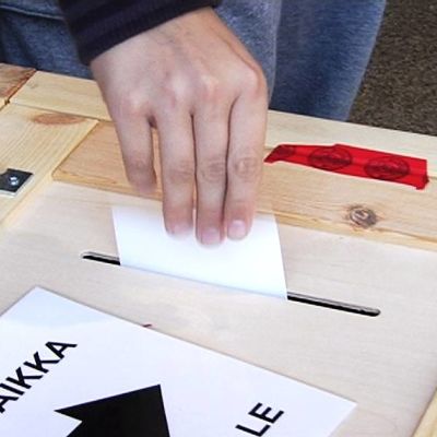 Äänestäjä tiputtaa vaalilipuketta uurnaan äänestyspaikalla.