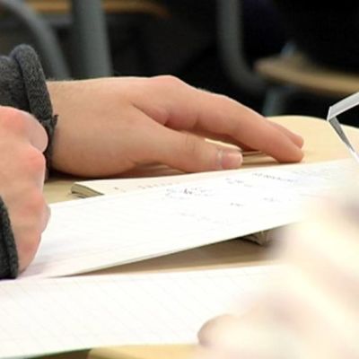 Opiskelija kirjoittaa muistiinpanoja.