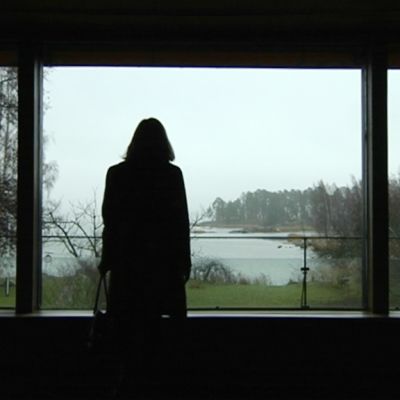 Nainen katsoo ikkunasta avautuvaa merimaisemaa.