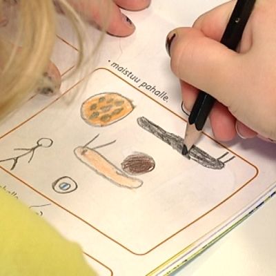 Lapsi piirtää esikoulukirjaan.