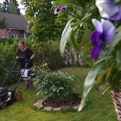 Nainen leikkaa nurmikkoa