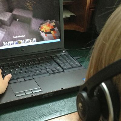 Kuvassa lapsi pelaa tieokonepeliä kuulokkeet korvillaan