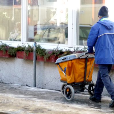 Kuvassa postinjakaja liukkaalla kadulla.