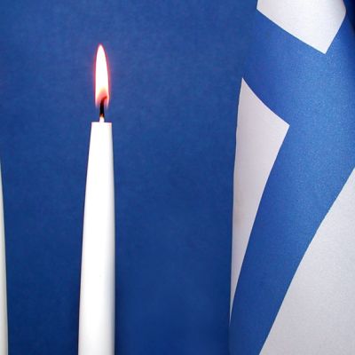 Kaksi kynttilää ja Suomen lippu.