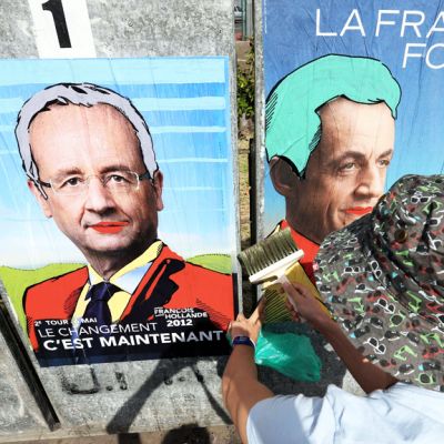 Henkilö kiinnittää käsiteltyjä vaalijulisteita seinään Saint-Denis de la Reunionissa 5. toukokuuta 2012.