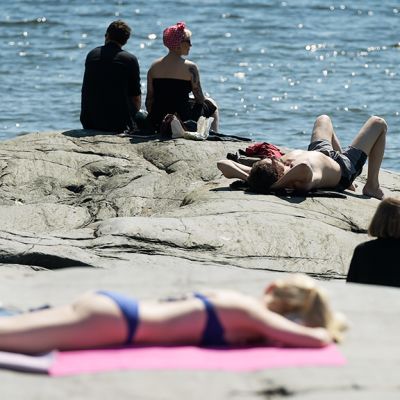 Ihmisiä ottamassa aurinko kallioilla.