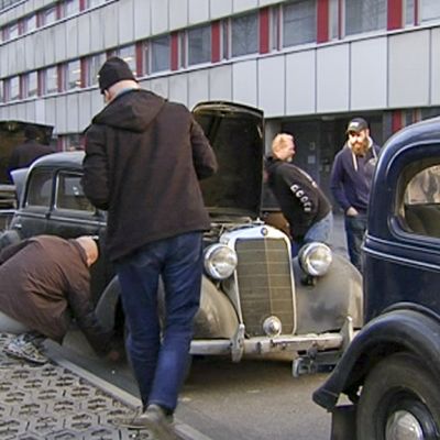 ihmiset tutkivat vanhoja autoja Ylen pihalla