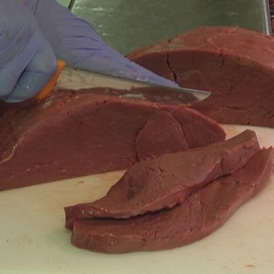 Lihamestari leikkaa hirvenlihaa kaupassa.