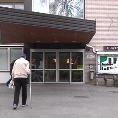 Ihminen kävelee terveysaseman edessä.