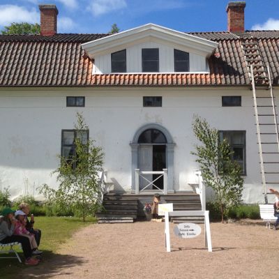 Kuvassa vaalea rakennus ja ihmisiä pihalla