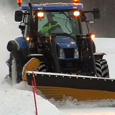 Traktori auraa lumista tietä