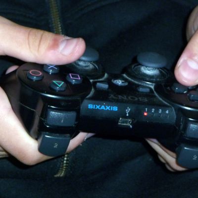 Nuori näppäilee Playstation-peliohjainta.