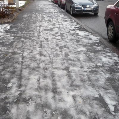 Kuvassa jäinen katunäkymä ja pysäköityjä autoja