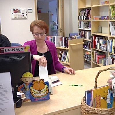 Asiakas lainaamassa kirjoja kirjastossa.