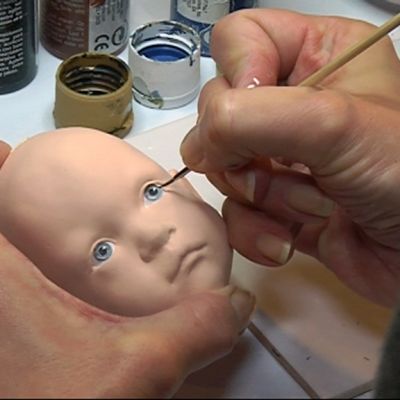 Nukketaiteilija Sirpa Ala-Louko maalaa nukelle ilmeikkäitä silmiä.