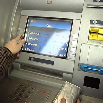 Henkilö käyttämässä pankkiautomaattia.