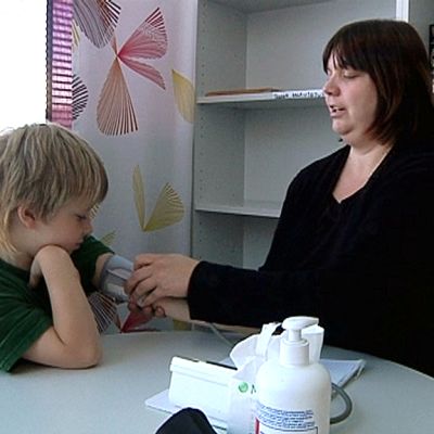 Tikkalan kylähoitaja Hanna Tiihonen mittaa ekaluokkalaisen verenpainetta.
