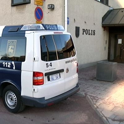 Ahvenanmaan poliisi seisoo autonsa vieressä.