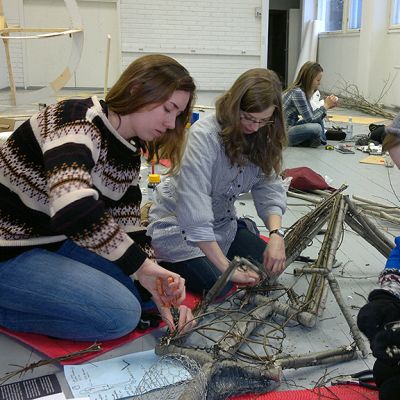 Kolme naisopiskelijaa tekee pajusta ihmishahmoa.