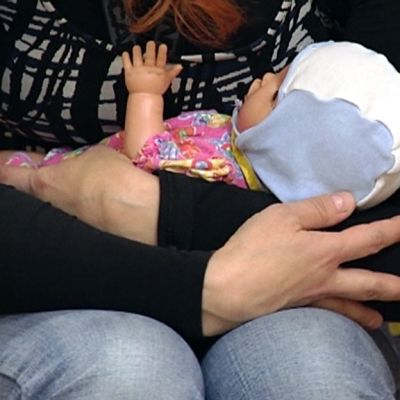 Lastenhoitaja pitelee nukkevauvaa käsissään