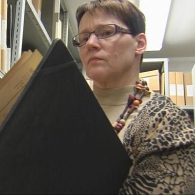 Tuija Korhonen katsoo arkistossa kirkonkirjaa