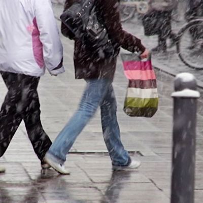 Kaksi naista kävelee kadulla räntäsateessa.