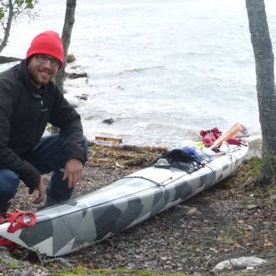 Erik Lerouge kyykyssä meren äärellä kajakkinsa vieressä.