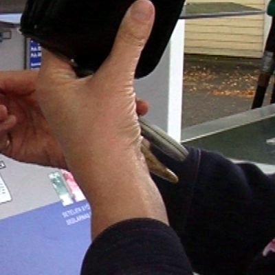 Nainen laittaa pankkikorttia maksuautomaattiin.