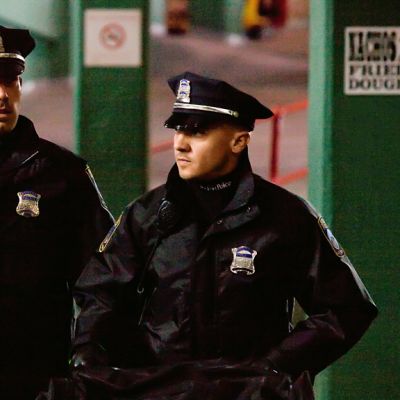 Kaksi poliisiunivormuihin sonnustautunutta miestä kävelee vihreäseinäisessä parkkihallissa.
