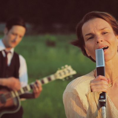 Laulaja Anna Järvinen musisoi laskevan auringon punertavassa valossa.