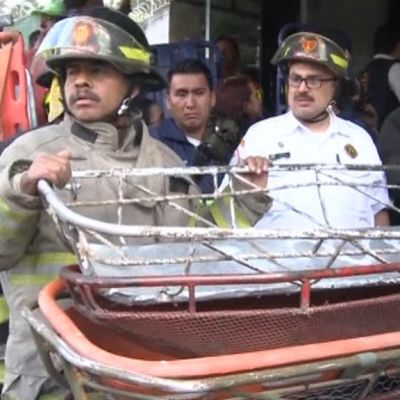 Pelastajat pitelivät telinettä, jolla ruumiita kannettiin palaneesta lastenkodista San José Pinulassa Guatemalassa keskiviikkona 8. maaliskuuta 2017. 