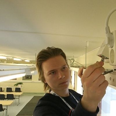 Datanomiopiskelija asentaa verkkokaapelia ah-stadionilla