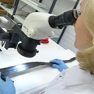 Konservaattori tutkii vanhaa miekkaa