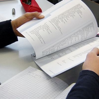 Koululainen selaa kirjaa tukiopetuksessa.
