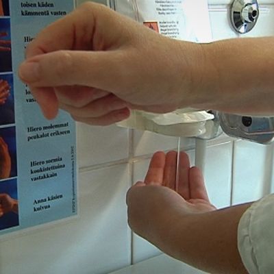 Nainen pesee käsiään desinfiointiaineella.