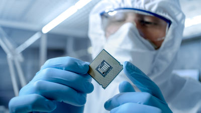 En person i skyddsdräkt inspekterar ett mikrochip.