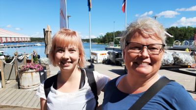 Pernilla Ekholm till vänster i vit t-skjorta, Marika Ekholm till höger i blå skjorta står i Nagu gästhamn.