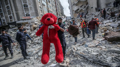 Palestinska räddningsarbetare bär bort en enorm teddybjörn ur ruinerna efter den förödande flygattacken som raserade tre bostadshus i Gaza City tidigt på söndag morgon.