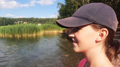 En flicka med blå keps tittar ut över havet vid en vassvik.