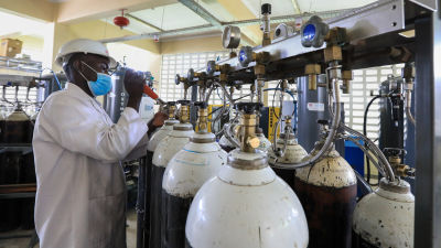 En anställd vid en syrgasfabrik i Kenya fyller syrgasbehållare.