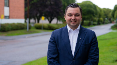 En ung man i mörkblå kavaj ler mot kameran