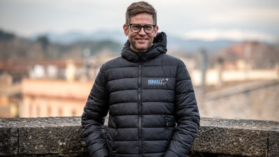 Kjell poserar för kameran på ett hustak. En stad skymtar oskarpt i bakgrunden.