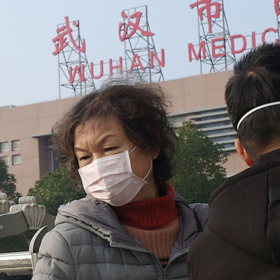 En kvinna och en man med munskydd utanför en hälsovårdscentral i Wuhan, Kina.